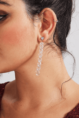 Close-up of Curveins Sparkle Gem Gold Bridgitte Earrings featuring cascading gold chains and crystal gems on a woman wearing a red dress.