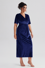 Curveins Plus Size Navy Blue V-Neck Velvet Maxi Dress with short sleeves and a flattering empire waist, styled with silver heels.