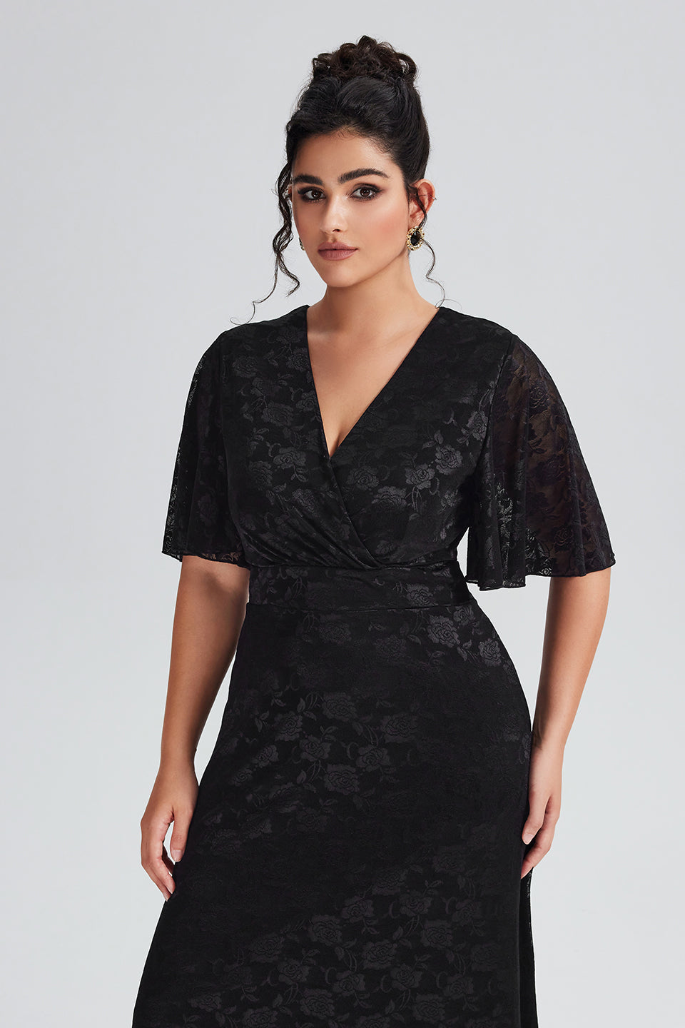 Close-up of delicate floral lace details and flutter sleeves on a plus-size black lace maxi dress, showcasing intricate design