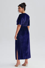 Back view of Curveins Plus Size Navy Blue V-Neck Velvet Maxi Dress showcasing a slit detail and soft velvet texture.